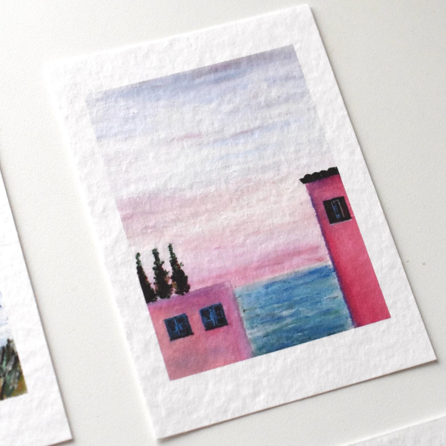 A6 oil pastel postcard of a pink seaside house with cypress trees and a pastel sunset sky — dreamy coastal landscape by HerPens.