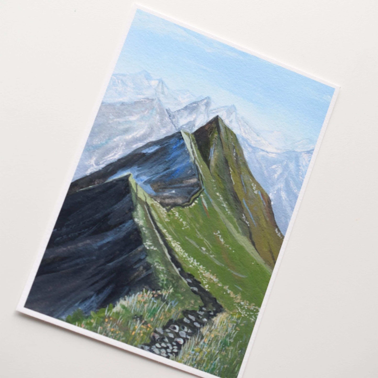 Painting of a mountain landscape with green slopes and snow-capped peaks on a white background