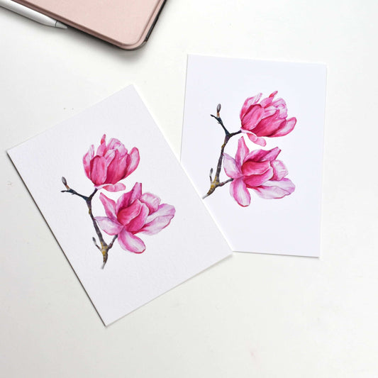 Side-by-side comparison of the “Watercolour Magnolia” postcard on smooth matte paper versus textured fine art paper, showing both finish options by HerPens.
