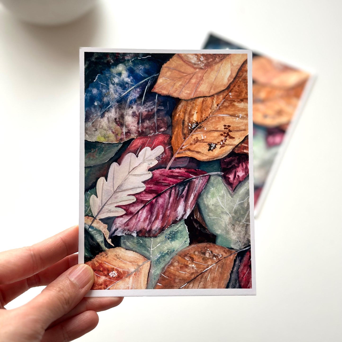 “Autumn Leaves” A6 gouache art print held in hand — delicate autumn leaves design on premium paper, ready to send or gift.
