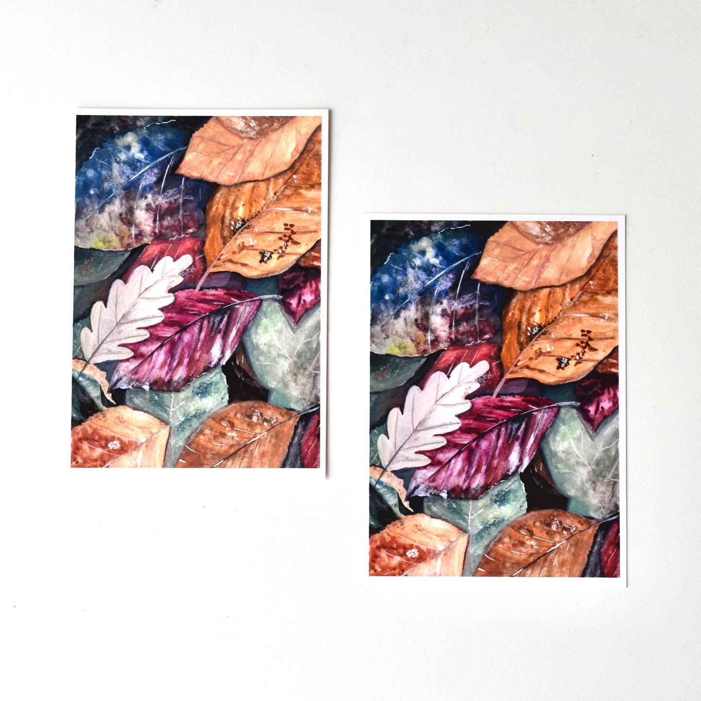 Side-by-side comparison of “Autumn Leaves” gouache postcards — smooth matte on the left and textured fine art paper on the right, showing color tone and finish difference.