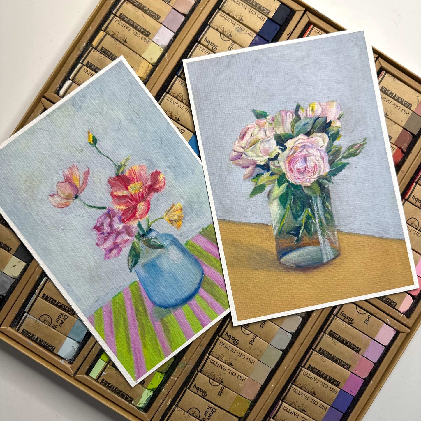 Two floral oil pastel art prints shown side by side on pastel stick background, flower vase paintings on textured fine art paper, HerPens