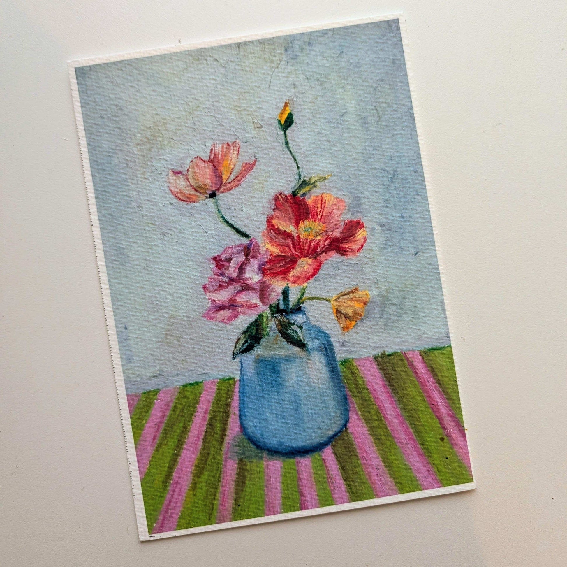 Postcard with a floral design featuring pink flowers in a blue vase on a striped background.