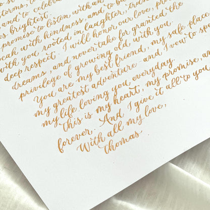 Handwritten gold ink calligraphy letter on white A4 paper captured at angle clean minimal aesthetic herpens