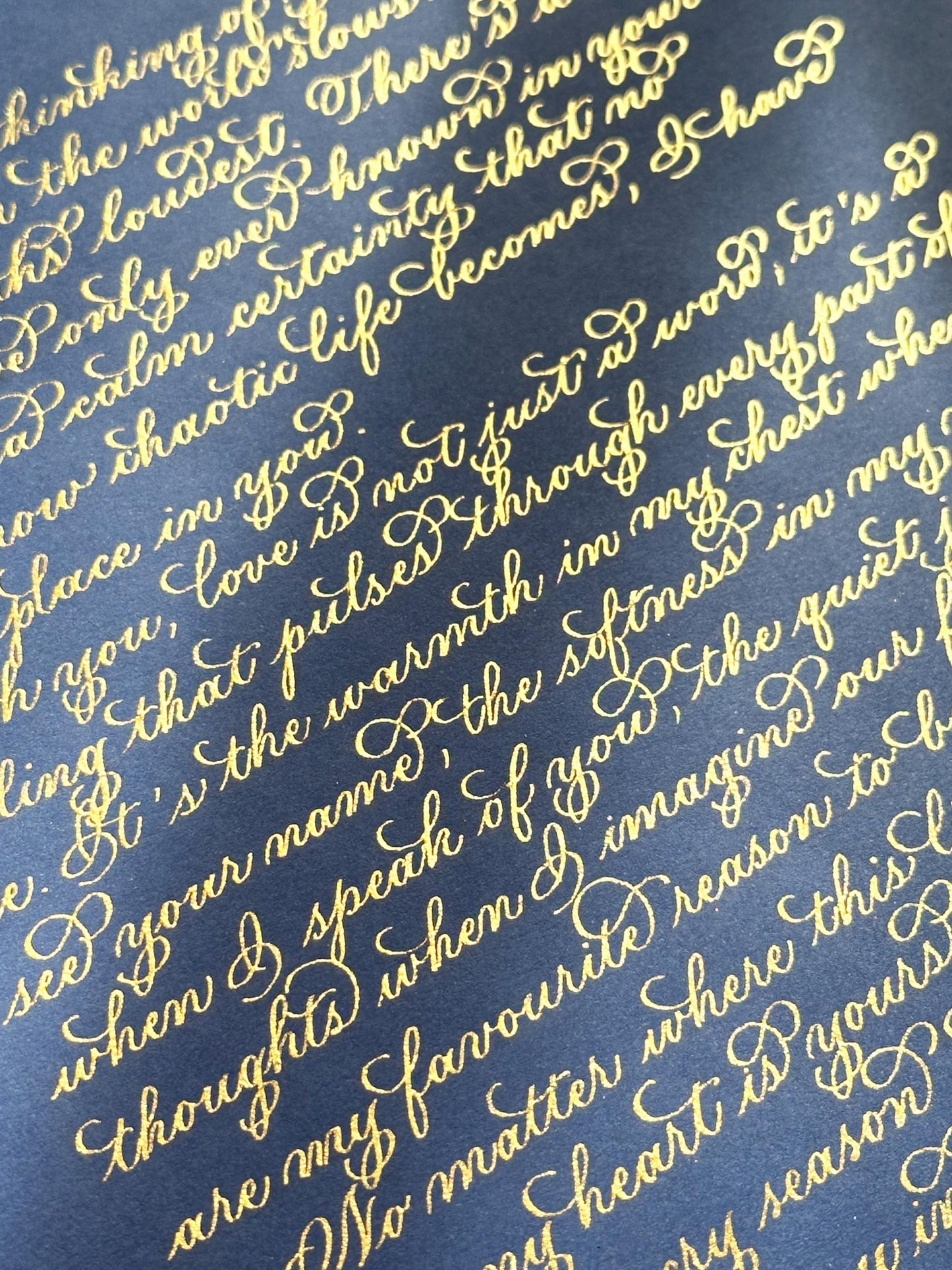 Handwritten detailed view of metallic gold flourishing calligraphy on deep navy paper elegant lettering herpens