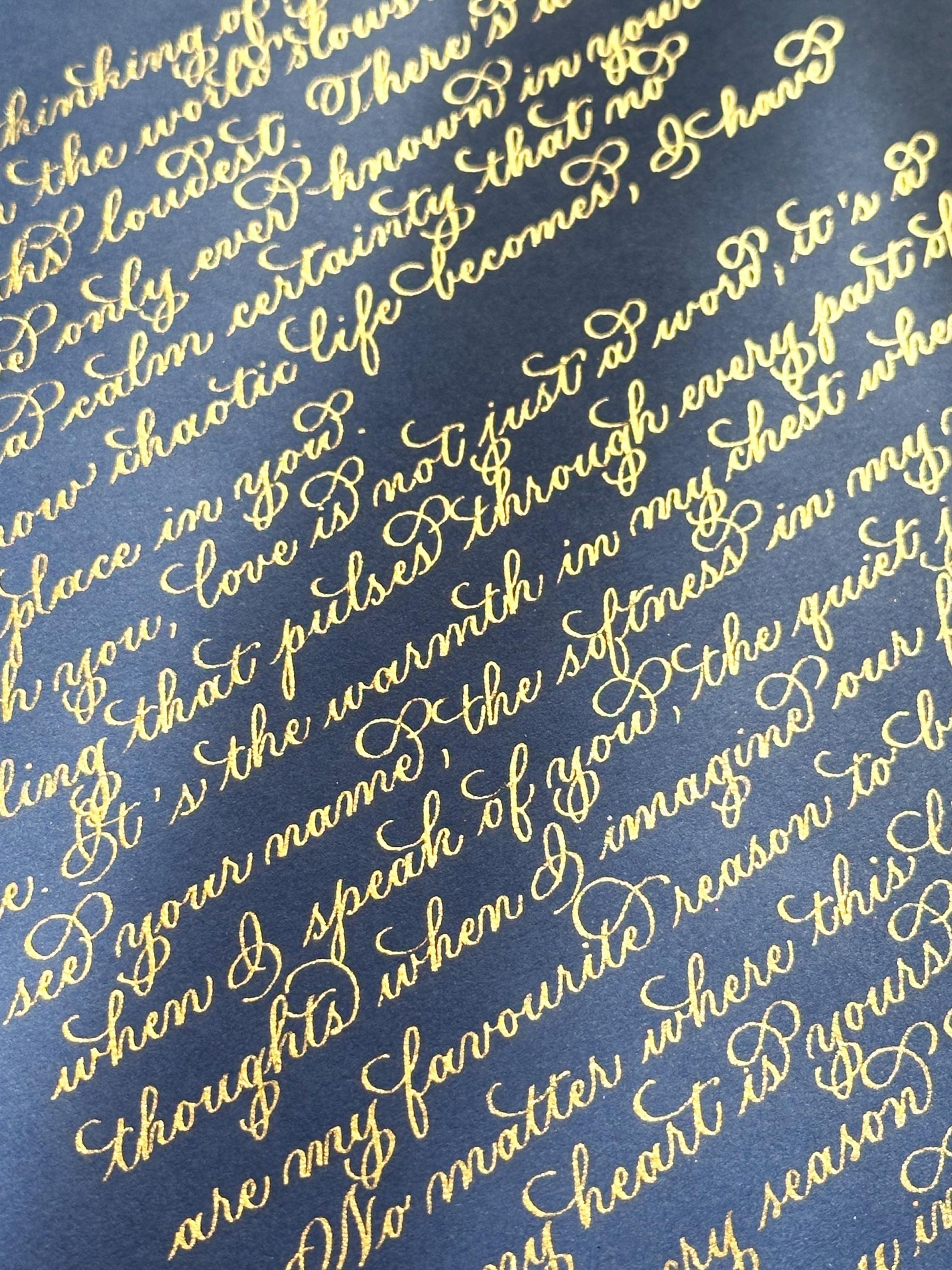 Handwritten detailed view of metallic gold flourishing calligraphy on deep navy paper elegant lettering herpens