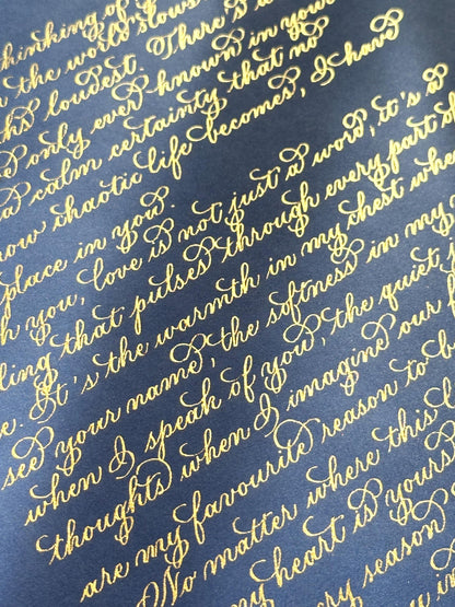 Handwritten detailed view of metallic gold flourishing calligraphy on deep navy paper elegant lettering herpens