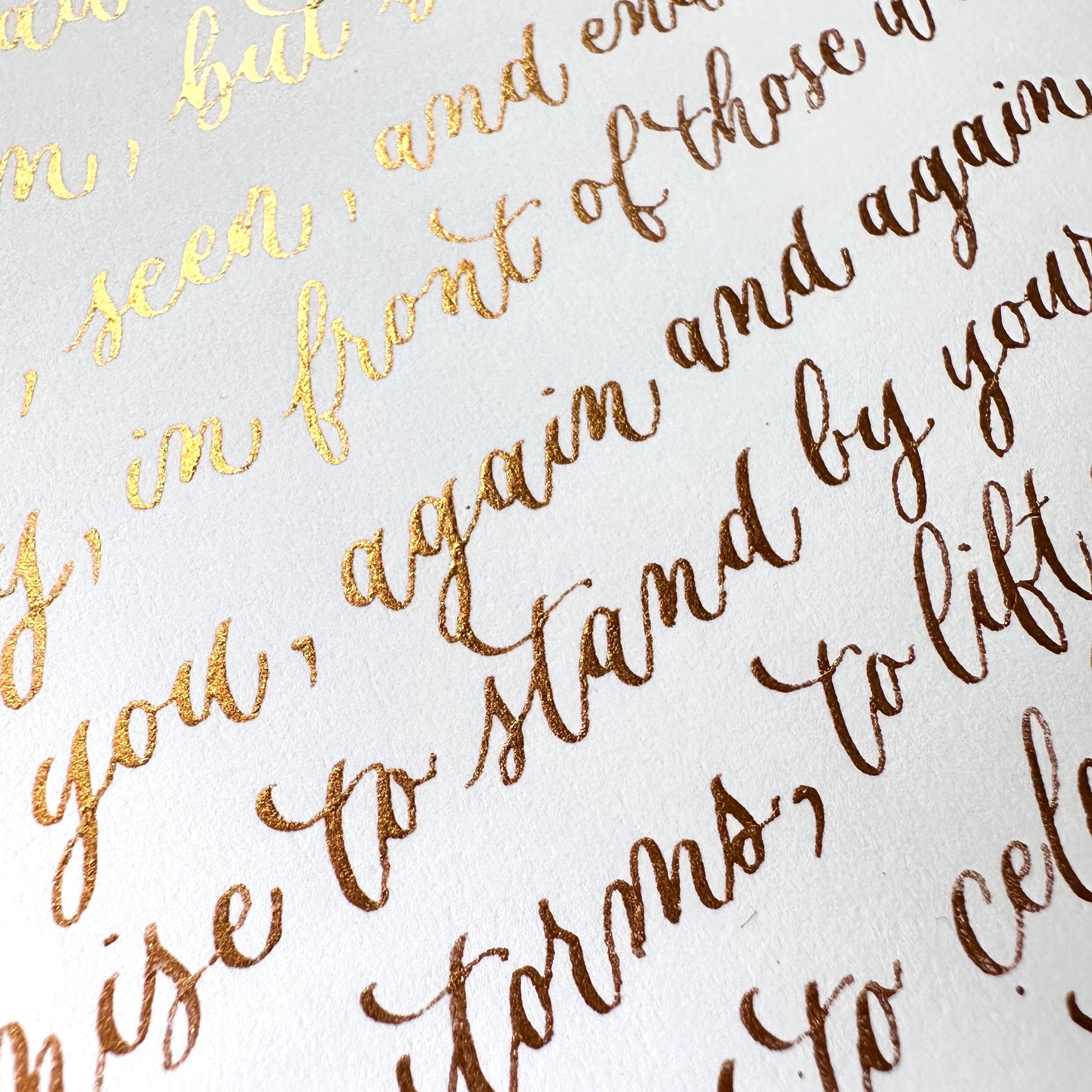Handwritten detailed view of gold ink modern calligraphy on white paper with soft elegant lettering herpens