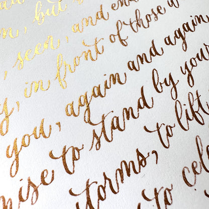 Handwritten detailed view of gold ink modern calligraphy on white paper with soft elegant lettering herpens