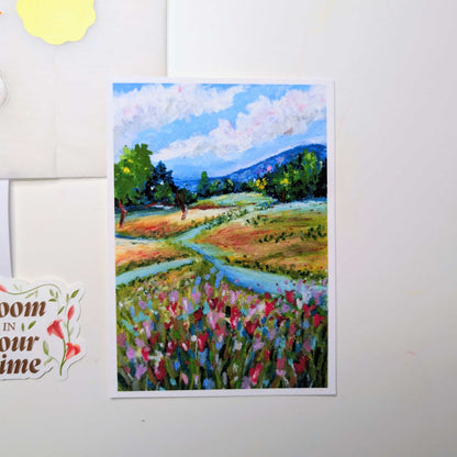 Colorful landscape painting of a field with flowers and trees on a white wall.