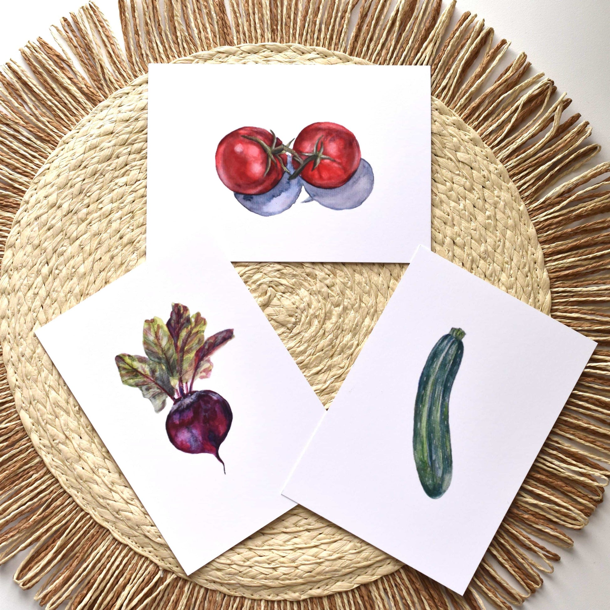 Three cards with illustrations of vegetables on a woven placemat.