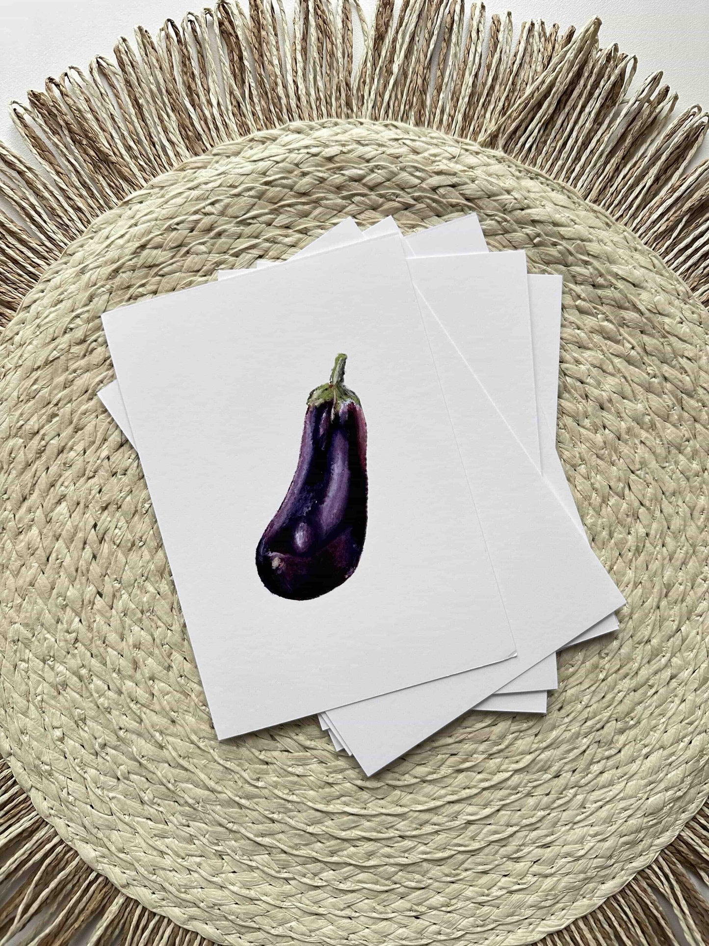 Eggplant on top of white cards on a woven placemat