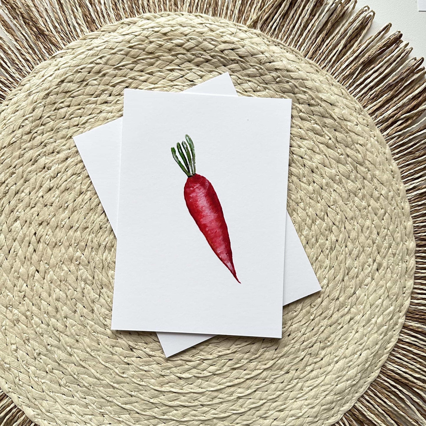 Note card with a red carrot illustration on a woven mat