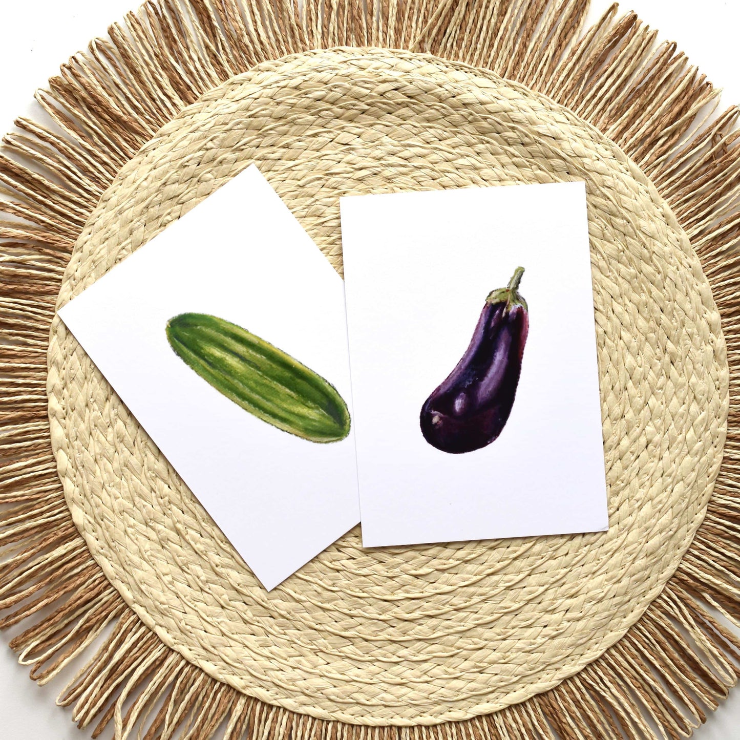 Two cards with images of a cucumber and an eggplant on a woven mat.