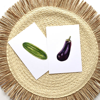Two cards with images of a cucumber and an eggplant on a woven mat.