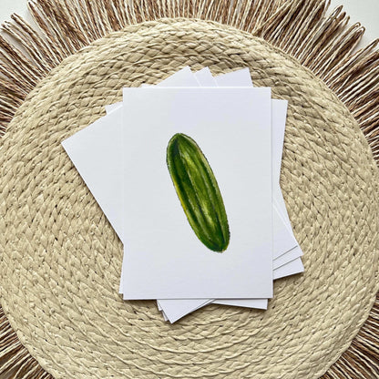 Stack of greeting cards with a cucumber illustration on a woven mat