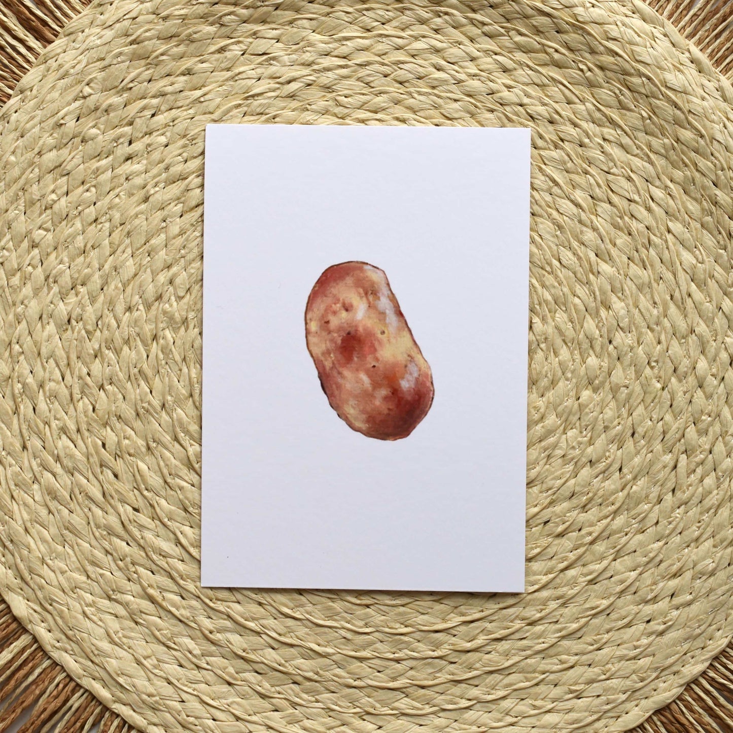 Postcard with a potato on a woven mat