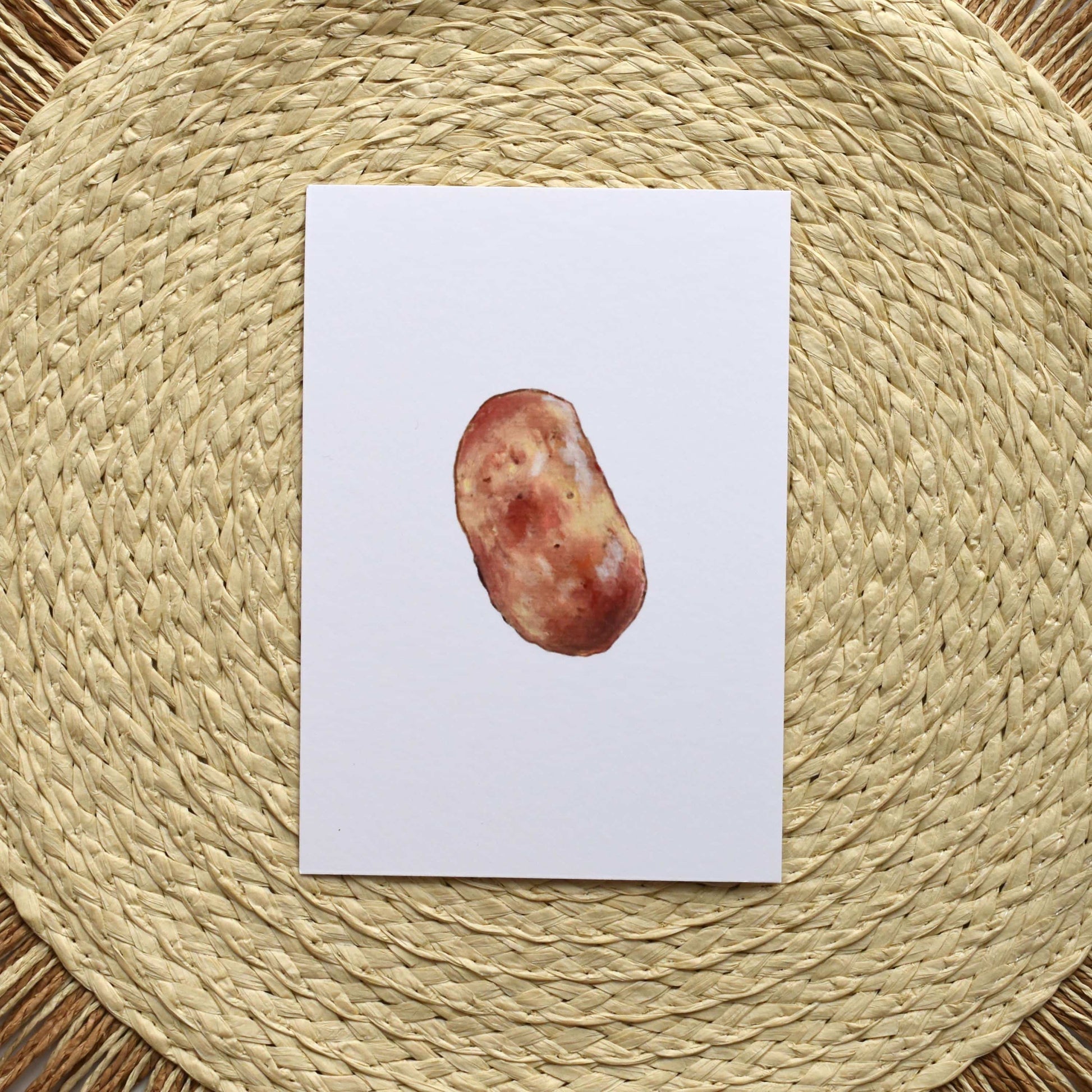 Postcard with a potato on a woven mat
