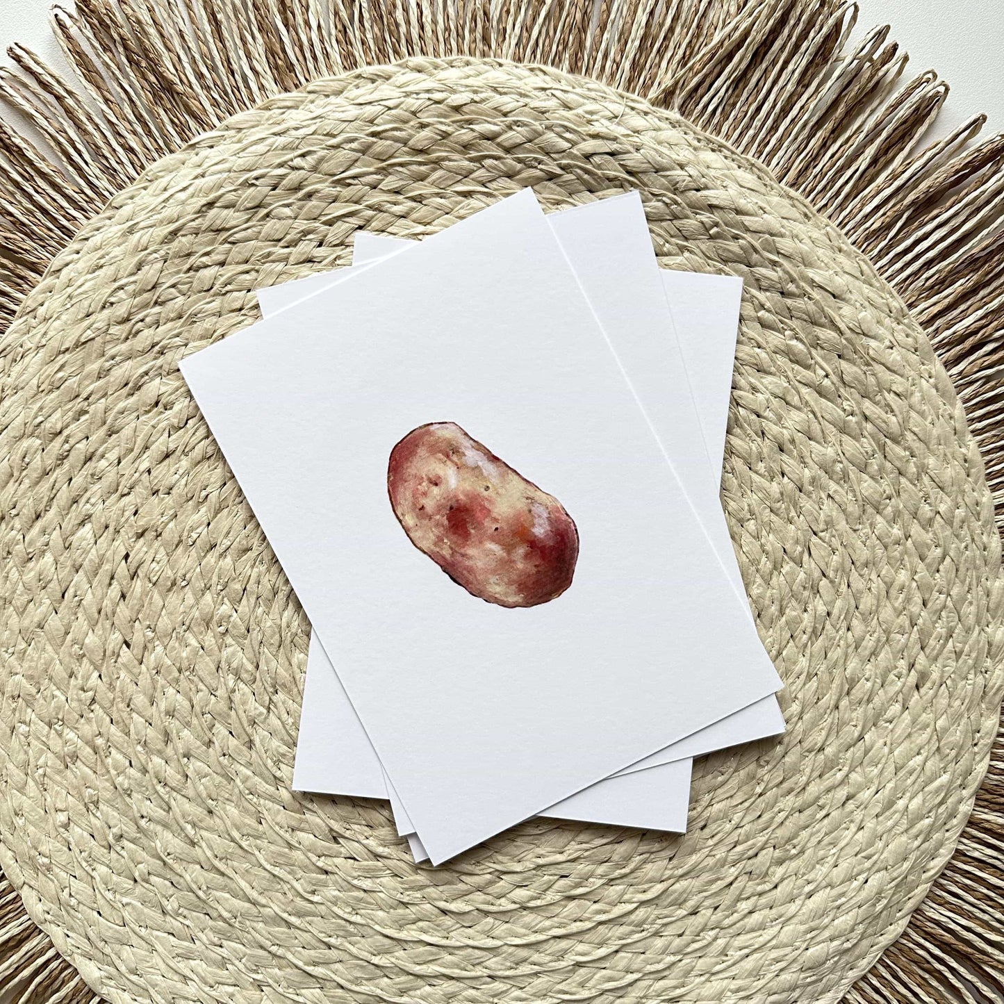 Stack of white cards with a red apple illustration on a woven mat