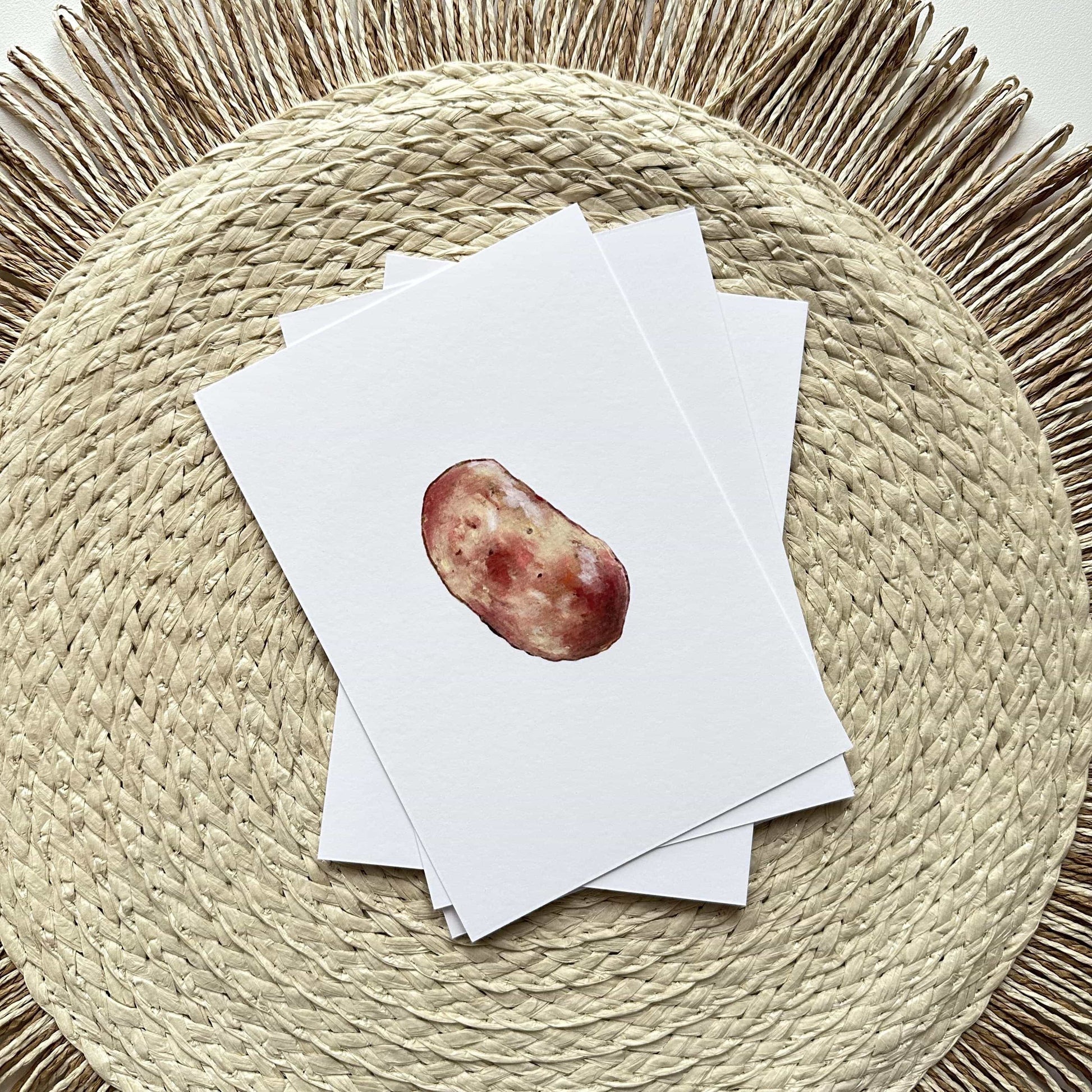 Stack of white cards with a red apple illustration on a woven mat
