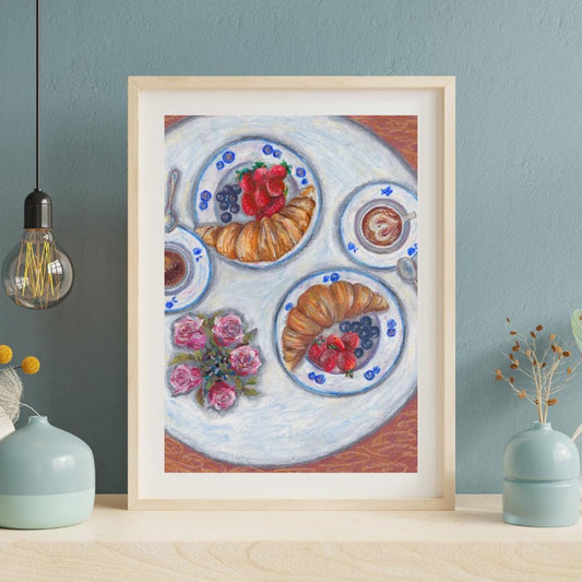 Framed oil pastel breakfast art print displayed on a teal kitchen wall, digital download artwork featuring croissants, berries and table setting, HerPens