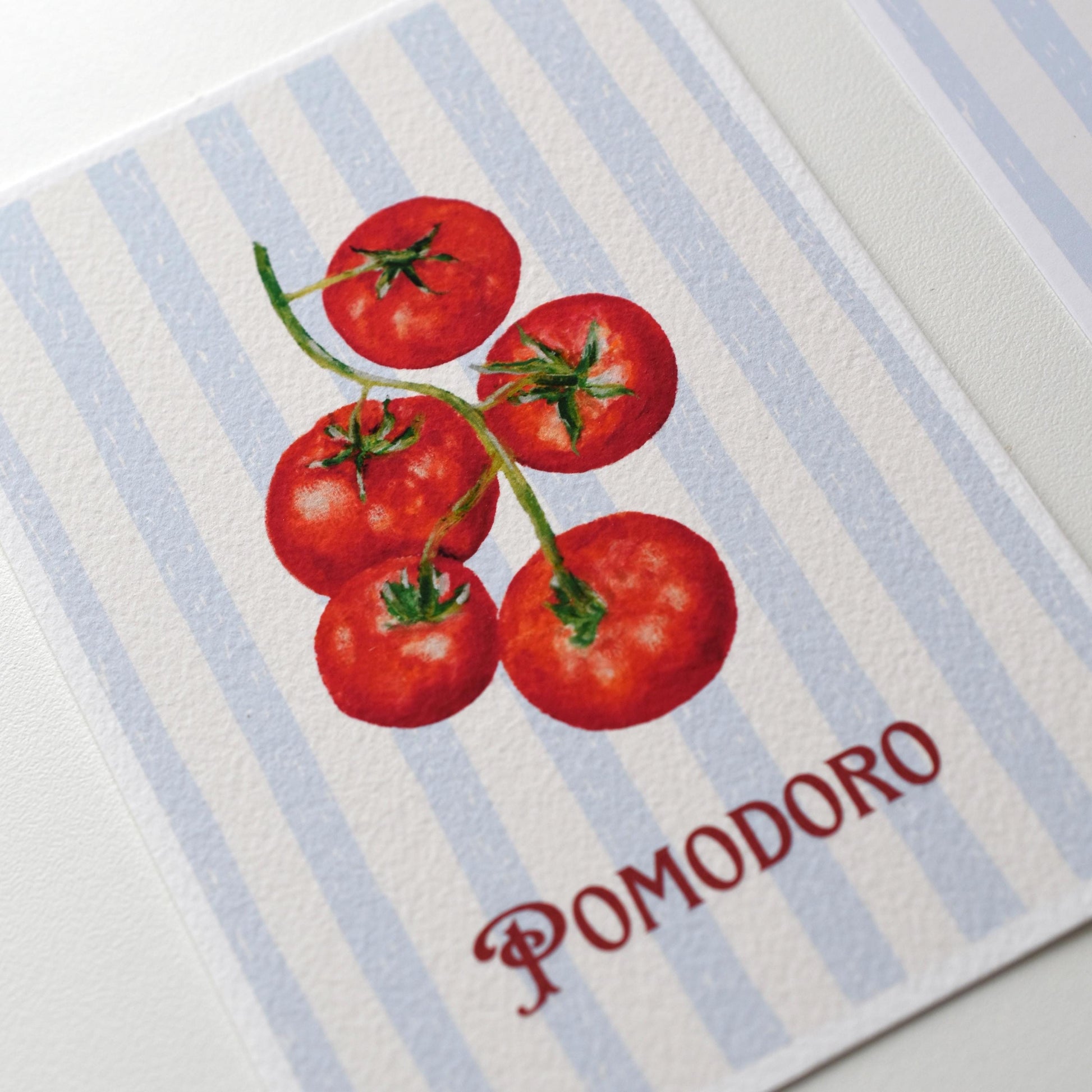 Close-up of the “Pomodoro” tomato postcard showing the textured fine art paper surface and oil pastel details from HerPens.