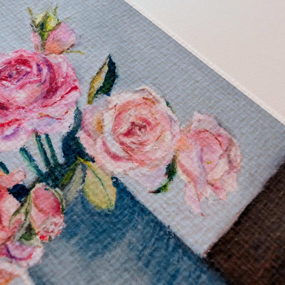 Close-up of a cross-stitched piece with pink roses on fabric.