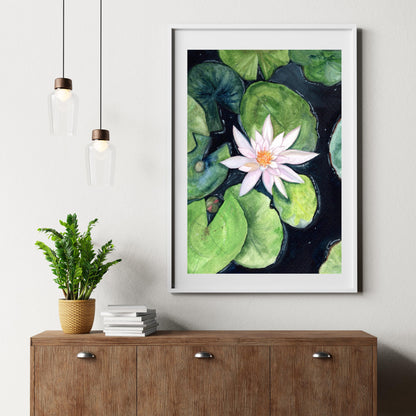 Framed Water Lily digital print styled on a soft beige wall with candle and book decor, gentle gouache lily illustration, HerPens