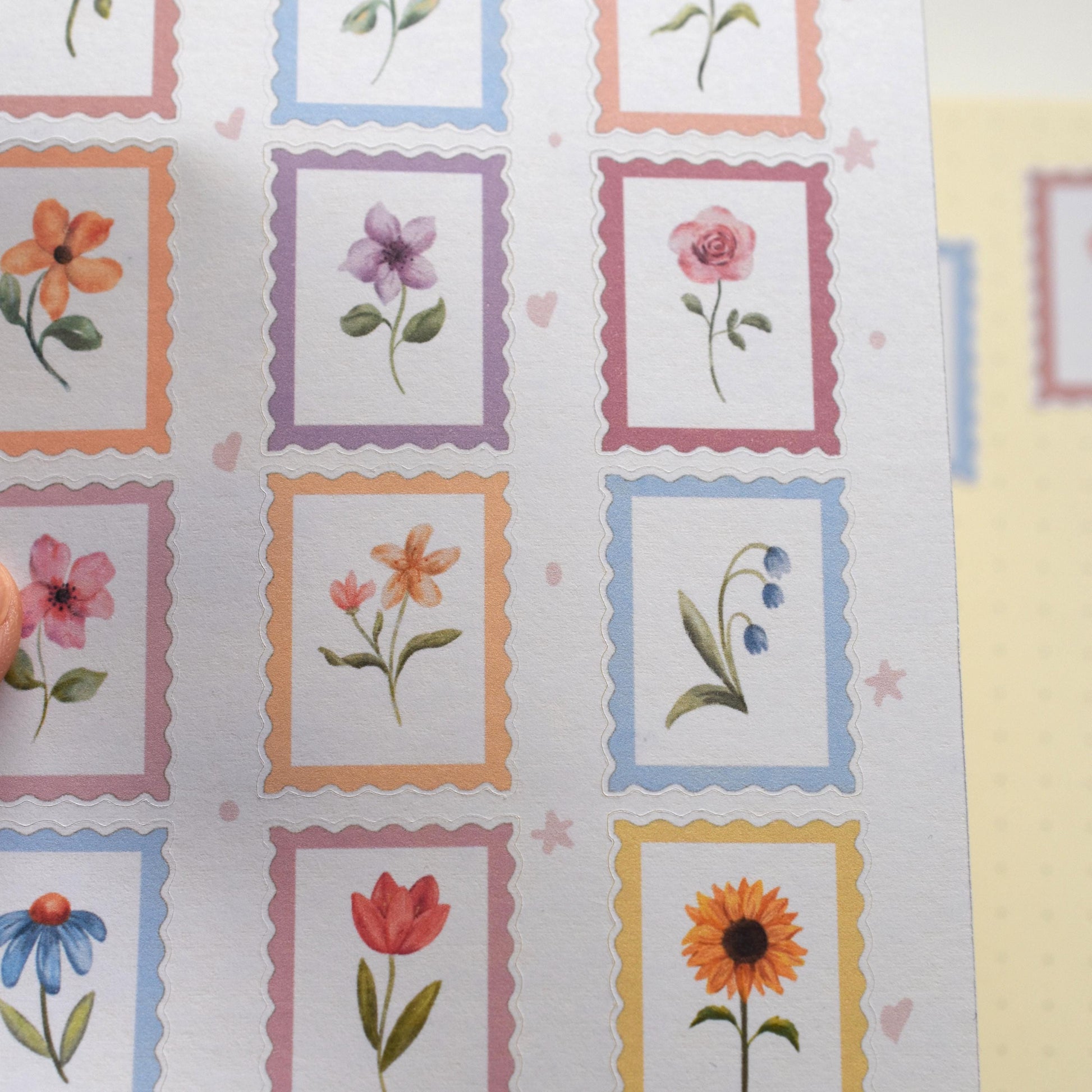 Angled view of botanical stamp sticker sheet with soft lighting highlighting watercolor finish herpens