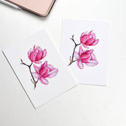 Side-by-side comparison of the “Watercolour Magnolia” postcard on smooth matte paper versus textured fine art paper, showing both finish options by HerPens.