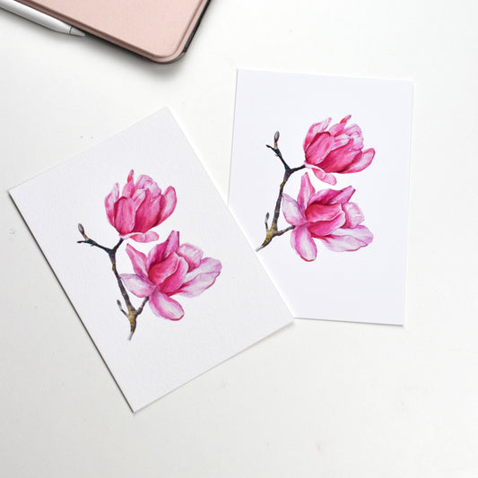 Side-by-side comparison of the “Watercolour Magnolia” postcard on smooth matte paper versus textured fine art paper, showing both finish options by HerPens.